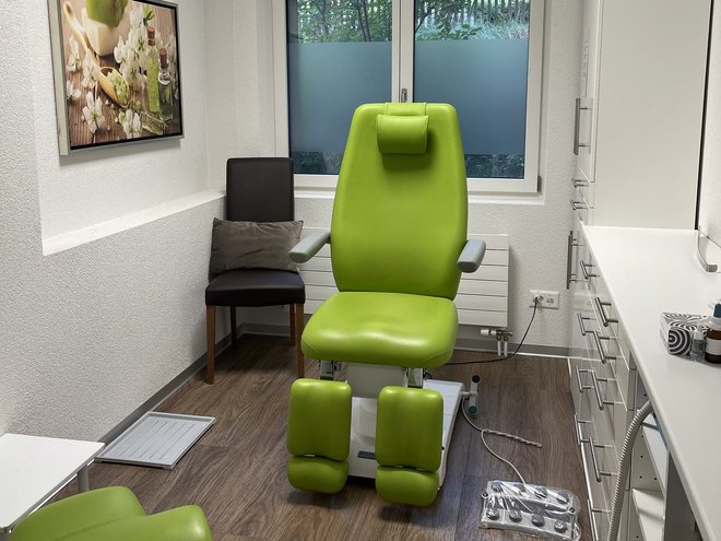 Eine Behandlungskabine der Podologie Elfenau mit grünem Behandlungsstuhl